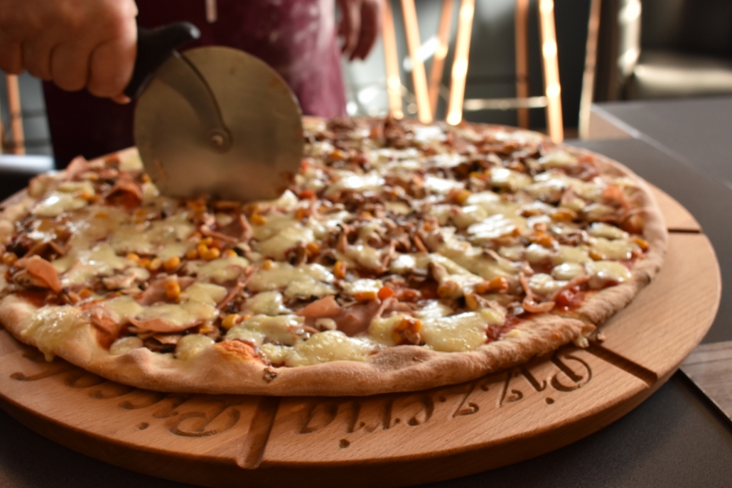 Krojenie dużej pizzy w Pizzerii Piccola